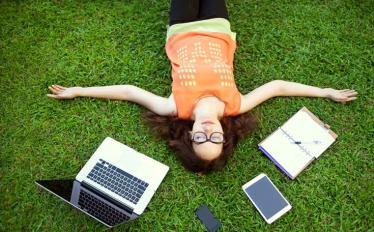 estudante deitada na relva junto a pc