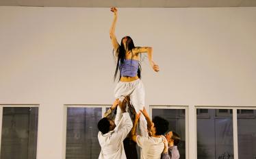 bailarina no ar, segura por dois bailarinos